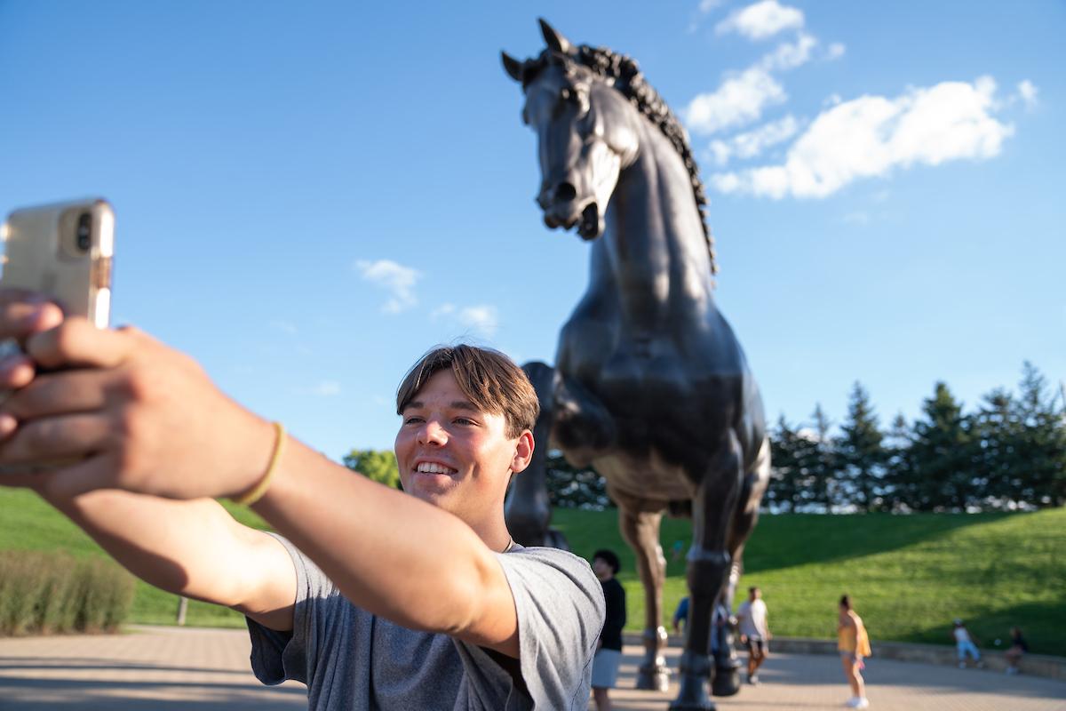 学生在弗雷德里克梅杰花园与马雕像自拍